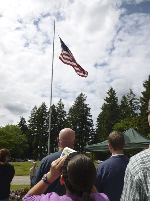 Community members watch as the American flag is raised. The presentation of colors and pledge of allegiance was led by Boy Scout Troops 525 and 585.