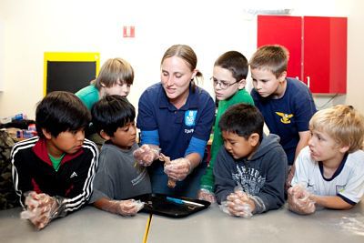 A Pacific Science Center teacher is surrounded by campers. Camps for Curious Minds will start July 8 at The Overlake School.