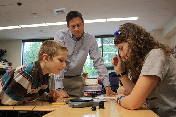 Washington Sen. Andy Hill of Redmond (center) and a group of eighth-graders from Stella Schola Middle School weigh and make observations on a piece of paper during a science lesson Tuesday morning.