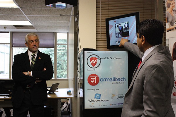 Amrelitech CEO Atul Hirpara (right) shows Congressman Dave Reichert different features of the Watch N Inform security system.