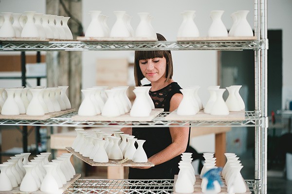 Material Good founder and CEO Lauren Burman places a tray of unpainted Little Shirley vases on a rack.