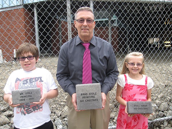 Second-graders Camden Gillespie (left) and Brooke Barr with Ben Rush principal Brad Stolz show off samples of engraved brick samples to be used to pave the school's new entryway.