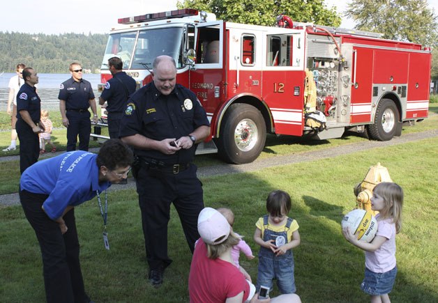 Redmond Police Department (RPD) Commander Mark Hagreen (center) and RPD volunteer Beverly Chabot (left) talks to mother Theresa Rosenfeld (pink hat) and her three daughters