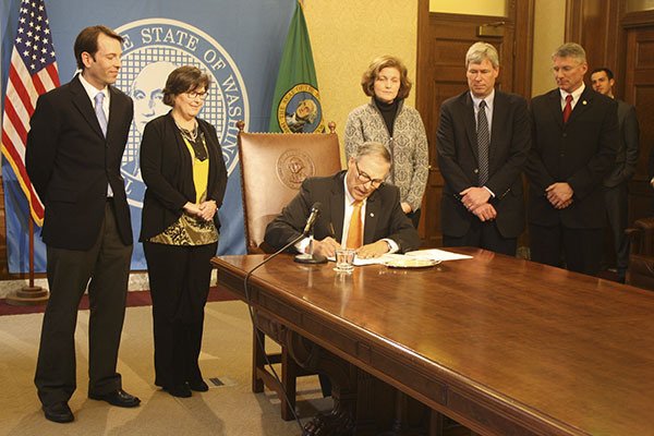 Gov. Jay Inslee (center) signs SB 6195