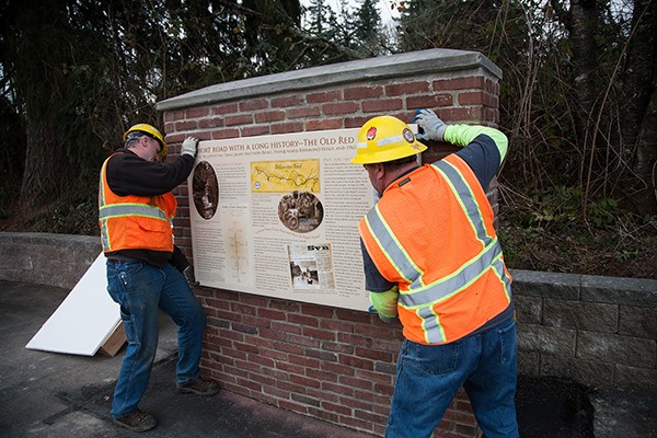 King County Road Services employees Lee Entrop (left) and Ron Bauman install the sign on the informational kiosk on 196th Avenue Northeast (the Red Brick Road).