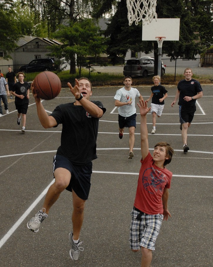 Redmond firefighter Josh Frei drives to the basket as Justin Camara (in red) defends during Wednesday's 'Hoops for Food' event