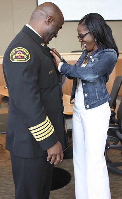 Andrea Smith (right) pins the Redmond Fire Chief badge on her husband Tommy Smith’s new uniform. Tommy is the City of Redmond’s new fire chief.