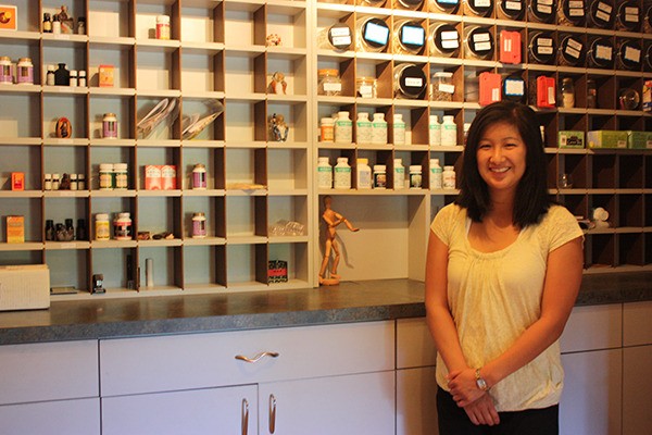 Debbie Yu stands in front of the various Chinese herbs she prescribes her patients.