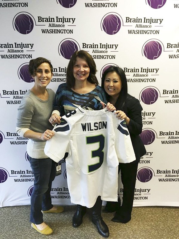 Wells Fargo’s Redmond branch recently donated a signed Russell Wilson Seattle Seahawks jersey to the Brain Injury Alliance of Washington. From left to right