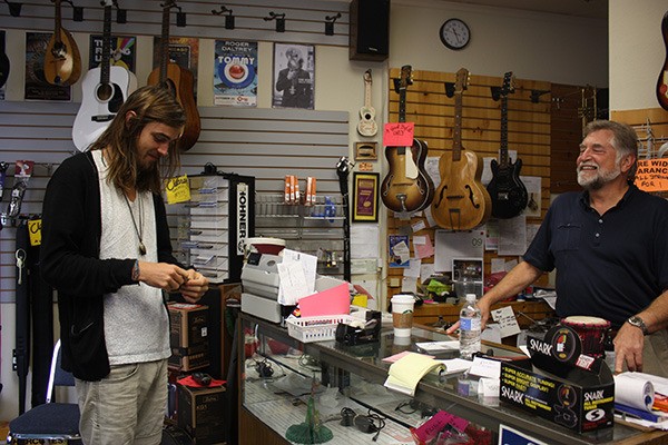 Customer Devin Pattison (left) admires a sticker he receives from Pacific Music owner Gary Weyand. The store in downtown Redmond will be closing by the end of this month after 26 years of business.