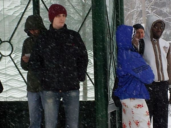 People wait at the downtown transit center during today's snow fall. Metro buses will be snow routes during tomorrow morning's commute.