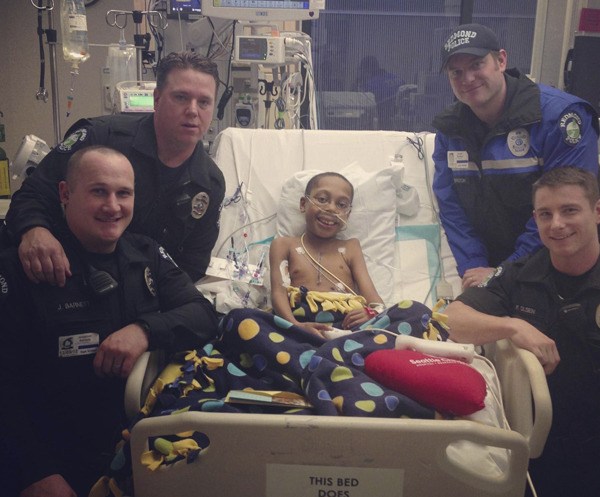 Jason Richards (center) receives a visit from the Redmond Police Department after his heart transplant surgery.