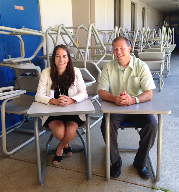 Evergreen Middle School associate principal Anne Balicki and new principal Robert Johnson sit at desks donated to the school by the Seattle Seahawks.